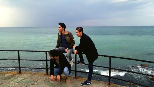 Full length of friends standing by sea against clear sky