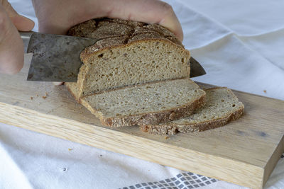 Close-up of hand holding bread on cutting board