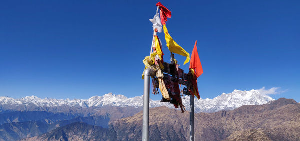 Traditional windmill on snowcapped mountain against blue sky