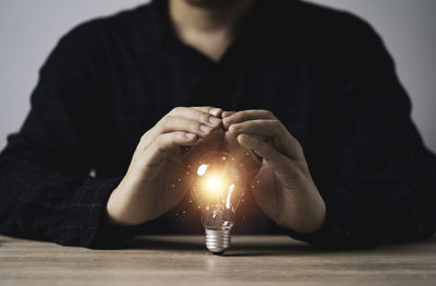Close-up of man holding illuminated light bulb