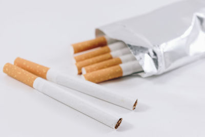 Close-up of cigarette on table against white background