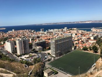 High angle view of cityscape by sea against clear sky