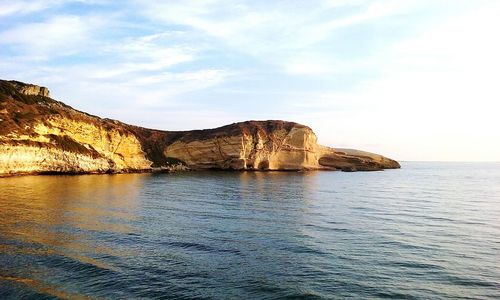 Rock formations by sea against sky