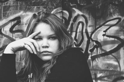 Portrait of young woman against graffiti wall