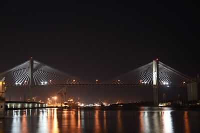 Illuminated bridge over river at night