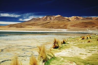 Scenic view of lake by mountains against sky at salar de uyuni