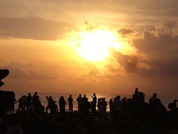 Silhouette people on beach against sky during sunset