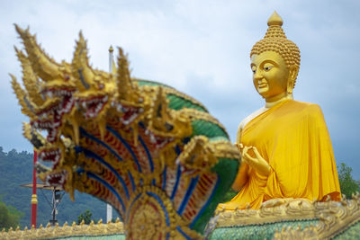 Low angle view of golden buddha statue at temple against sky