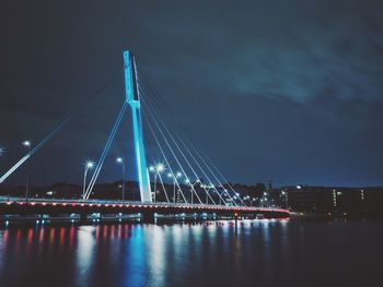 Illuminated suspension bridge over river at night