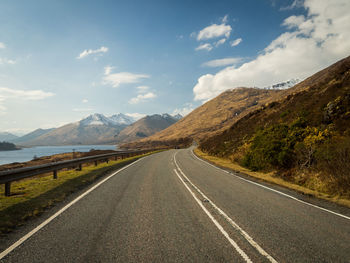 Empty road by mountains against sky