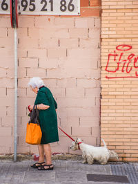 Man with dog standing by text on brick wall