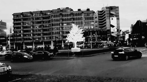 Cars on street in city against sky