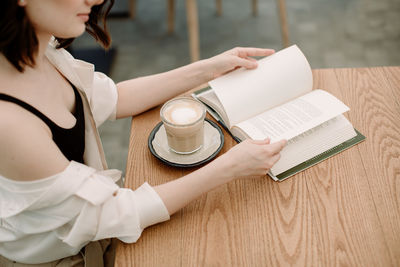 High angle view of woman holding coffee cup on table