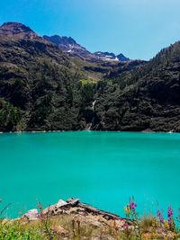 Scenic view of lake by mountains against blue sky