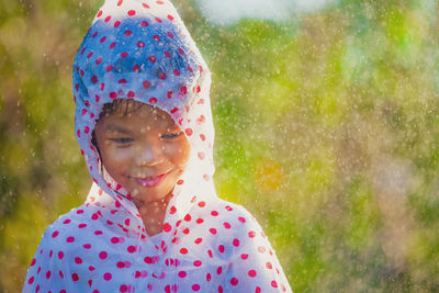 Girl wearing raincoat standing in park during rainfall