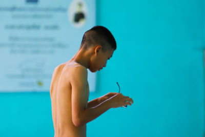 Side view of man holding eyeglasses at swimming pool