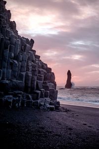 Stack of rocks at beach against sky during sunset