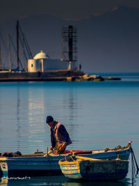 Man on boat moored in sea against sky