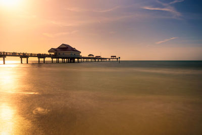 Lifeguard hut on beach against sky during sunset