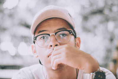 Portrait of young man wearing eyeglasses and cap while sitting outdoors