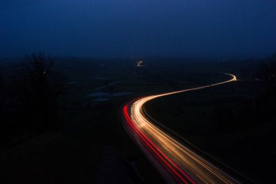 Light trails on road against clear sky at night