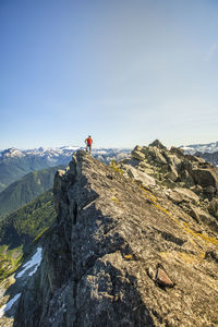 Climber stands on the summit of a rocky mountain peak, b.c. canada