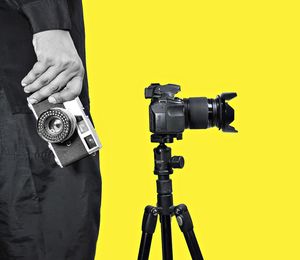 Man photographing with camera against gray background