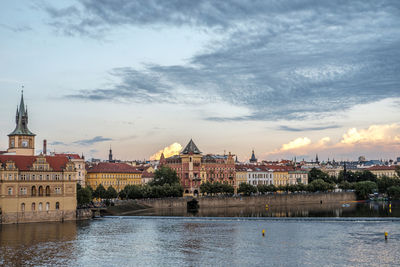 River in city against sky during sunset