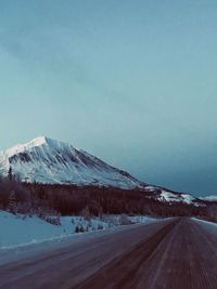 Road by snowcapped mountain against sky