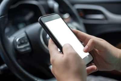 Cropped hands using mobile phone while driving car