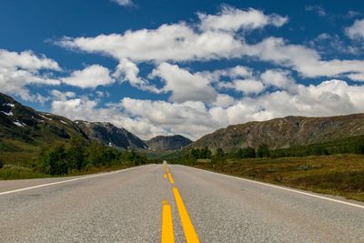 Diminishing perspective of empty road against cloudy sky