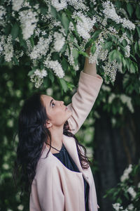 Young woman touching flowers on plant