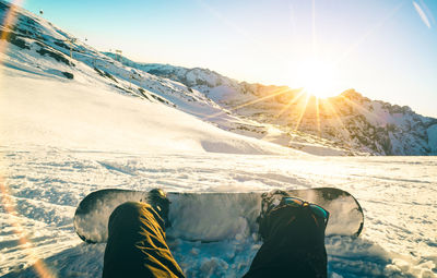 Low section of man snowboarding on mountain during sunny day