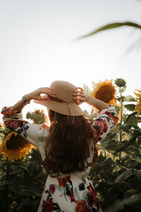 Rear view of woman by flowering plants against sky