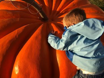 Rear view of boy standing by orange umbrella