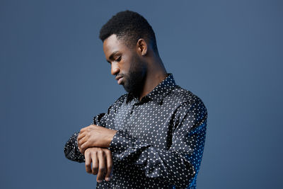 Side view of man looking away against blue background