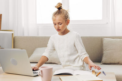 Boy using laptop while sitting on sofa at home