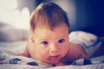 Portrait of cute baby lying on bed at home