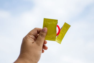 Close-up of man holding condom outdoors