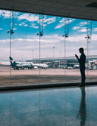 Man standing by airplane window at airport