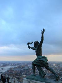 Statue of city against cloudy sky