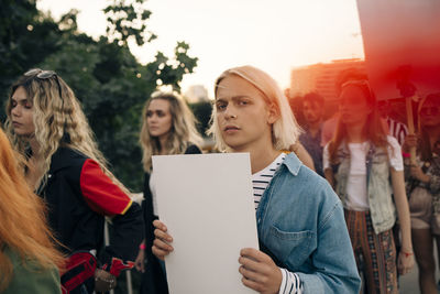 Portrait of young man with friends protesting in city