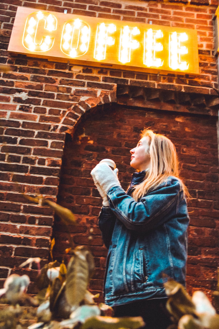 WOMAN STANDING AGAINST WALL