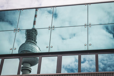 Reflection of tower and clouds on glass structure