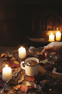 Cup of coffee with marshmallows on dark background with candle light