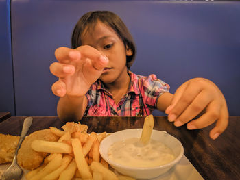 Close-up of girl having french fries in restaurant