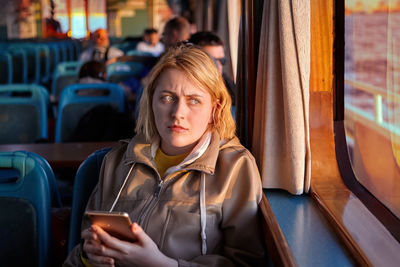 Portrait of woman using mobile phone while sitting in bus