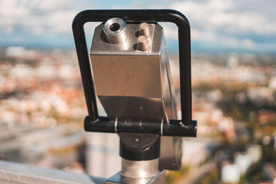 Close-up of coin-operated binoculars against cityscape