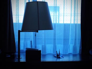 Lamp by paper crane on table at home