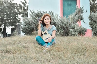 Portrait of smiling young woman playing guitar